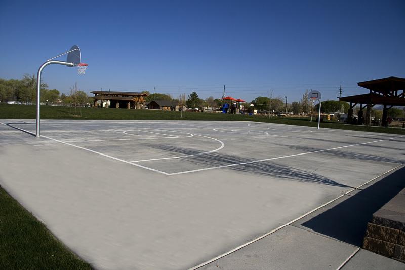cement basketball court with lines drawn and one hoop showing