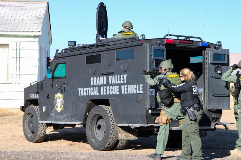 Two SWAT Team Members stand behind the Grand Valley Tactical Rescue Vehicle during a training exercise.
