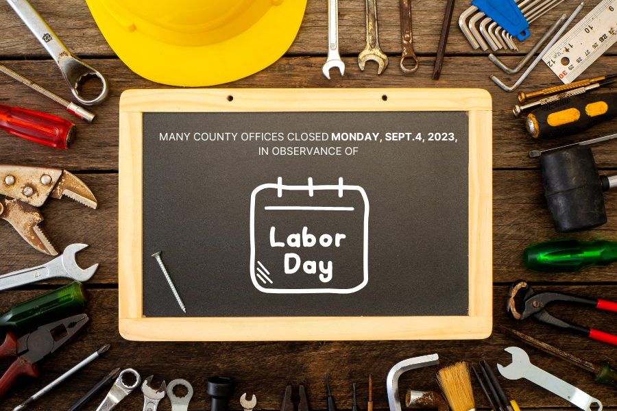 Chalk Board reading "Mesa County administrative offices will be closed Monday, Sept.4, 2023, in observance of Labor Day." with tools and other objects around chalk board.