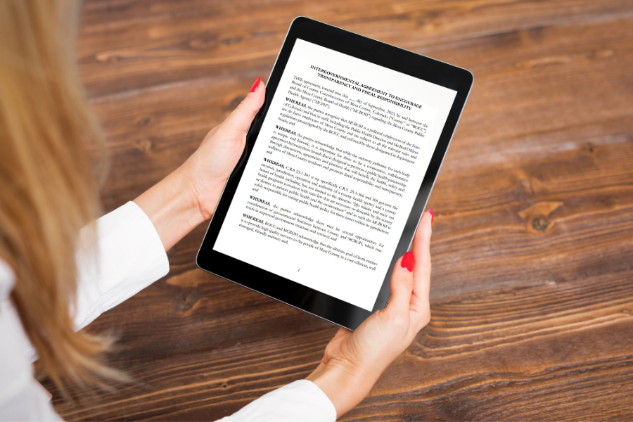 Woman's hands holding Ipad with document on screen.