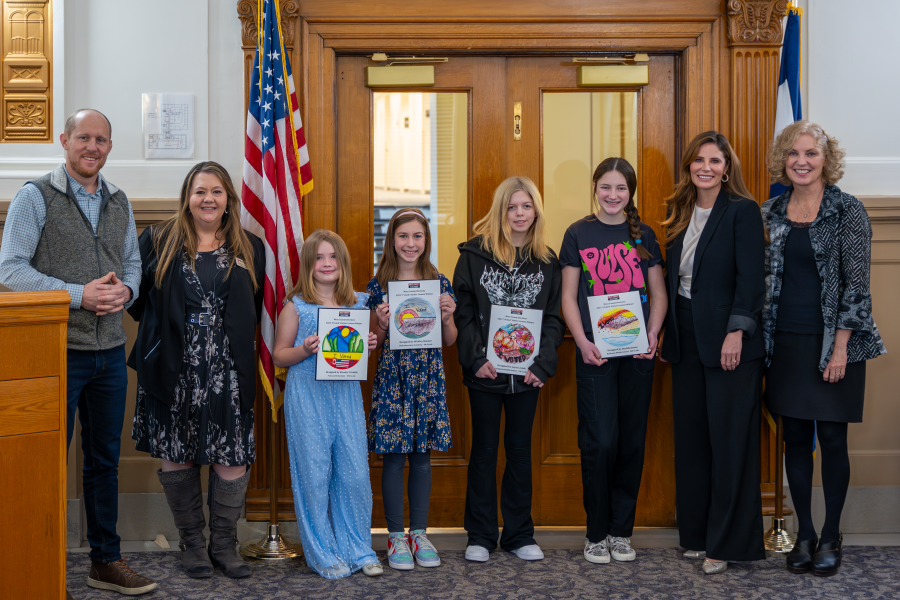 The Board of Mesa County Commissioners stand next to 2024 "I Voted" Sticker Design Contest winners. 