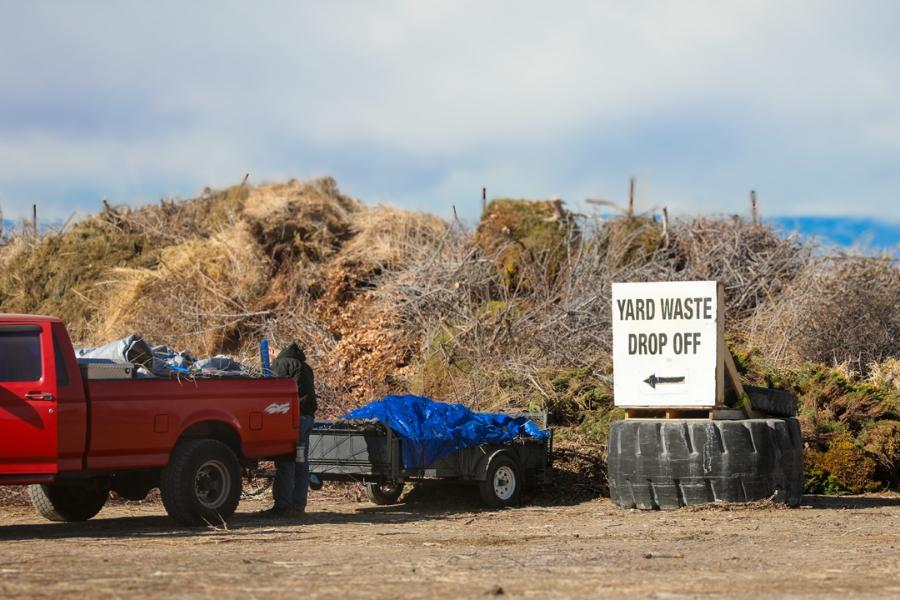 Yard waste behind a red truck with white sign reading, "Yard Waste Drop Off."