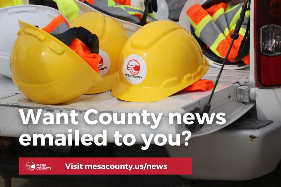 Yellow hard hats with Mesa County logo on them sit in back of white truck bed and white text reads, "Want County news emailed to you? Visit mesacounty.us/news."
