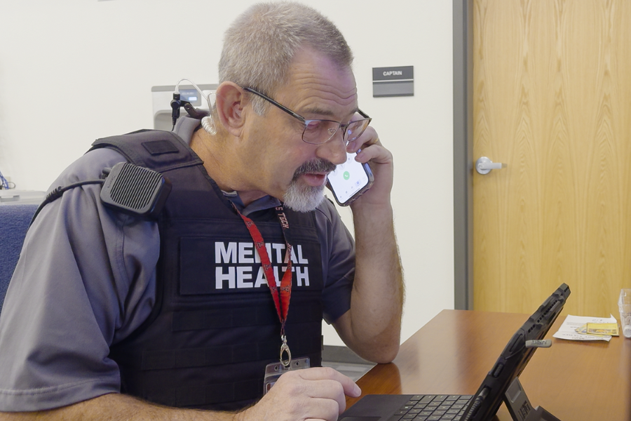 A man with a mental health vest takes a call for behavioral health services