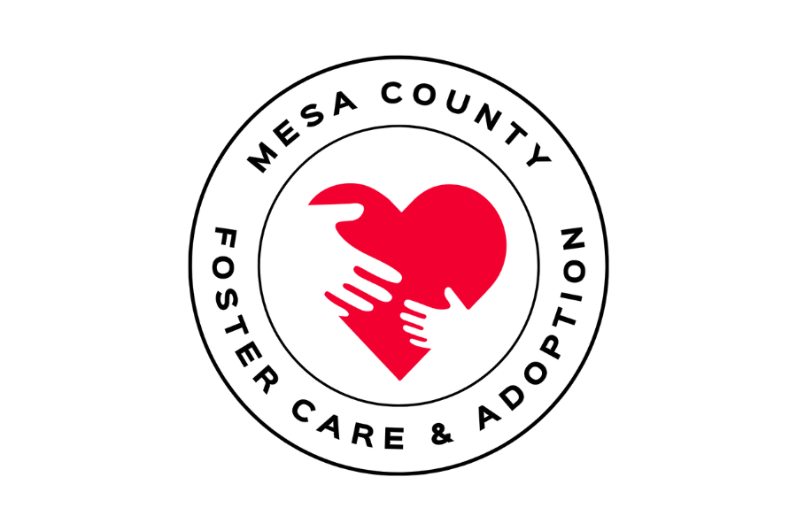 Red heart with white hands in the middle and black text in a circle around the heart reading, "Mesa County Foster Care & Adoption."
