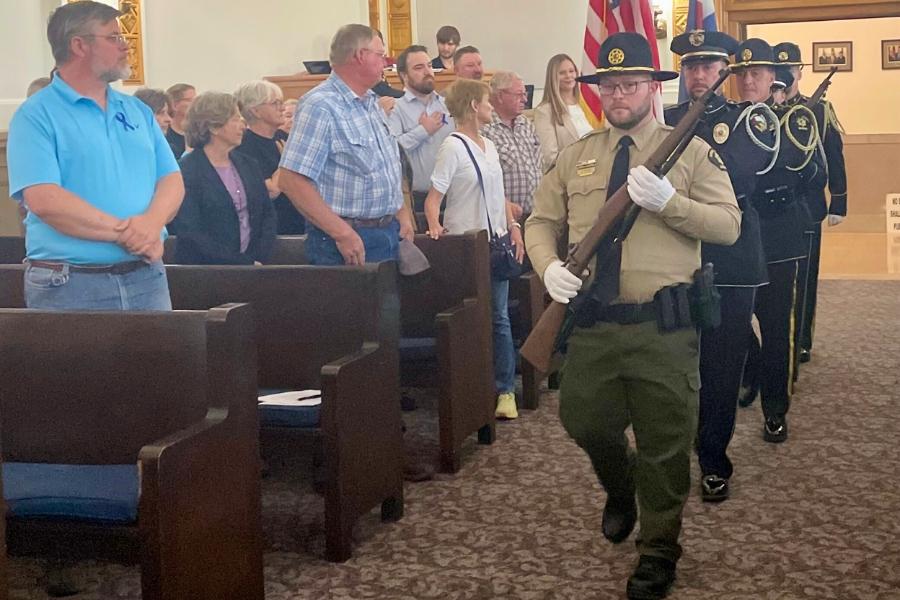 Mesa County Sheriff’s Office and Grand Junction Police Department combined Honor Guard walking through Mesa County public hearing room in straight line. 
