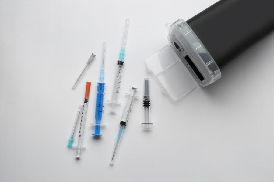 A picture of needles and a sharps disposable containers 
