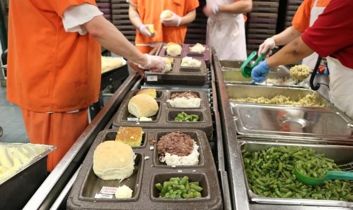 Photograph of inmates preparing trays of food for the Inmate Food Service program