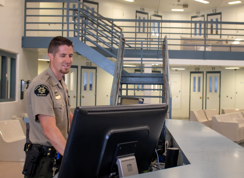 Photograph of a Mesa County Sheriff deputy working at a computer in one of the Detention Facility pods