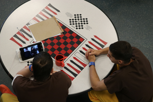 Photograph of two male inmates sitting at a game table