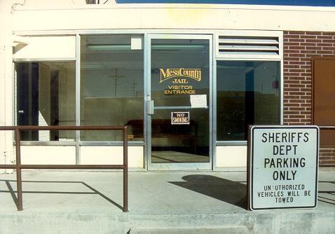 Historical photograph of the old Mesa County Jail Visitor Entrance from the outside with a sign for Sheriffs Department parking only unauthorized vehicles will be towed