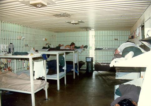 Historical photograph of inside of a group jail cell with bunk beds