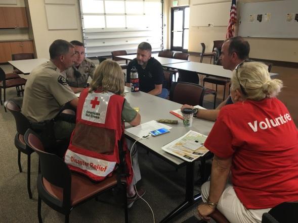 Photograph of an emergency management meeting showing a group of Law Enforcement representatives, volunteer, and American Red Cross disaster relief worker