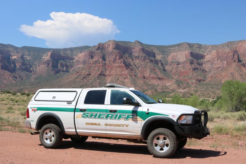 Photograph of Mesa County Sheriff Vehicle on dirt road with mountains in background