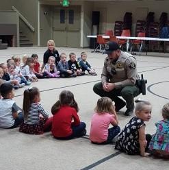 Photograph of Mesa County Sheriff Deputy speaking to a group of children in a school gymnasium 