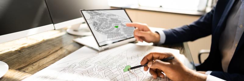 Photograph of two men in meeting discussing subdivision layout Blue Print on paper and tablet