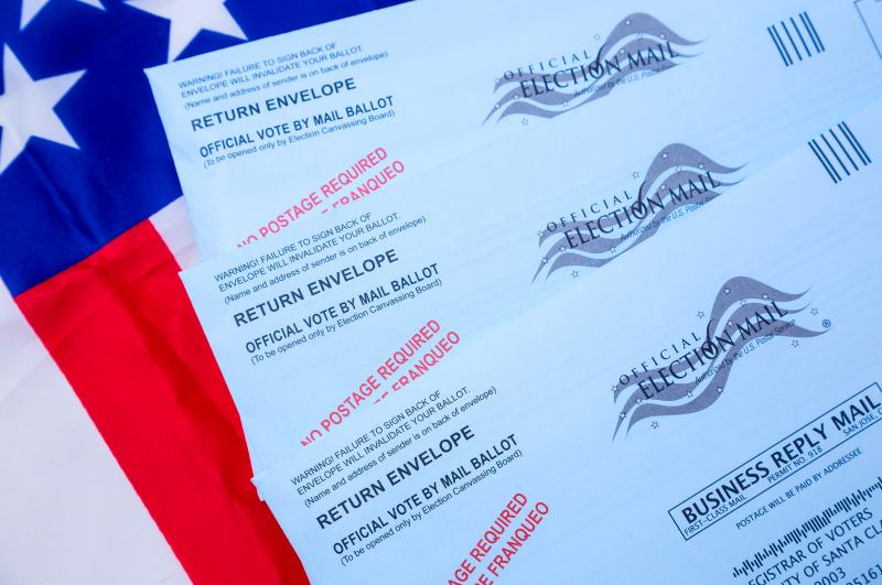 Photograph of three Election Mail Ballot envelopes on top of a United States Flag