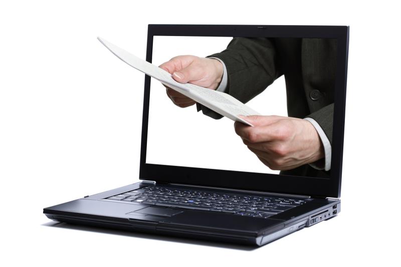 Photograph of a Laptop with Hands holding a report through the monitor