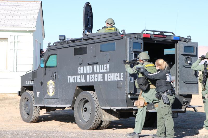 Photograph of Grand Valley Tactical Rescue Vehicle with a deputy standing up through hole in the roof of the vehicle and two deputies standing at the rear of the vehicle pointing gun and rifle