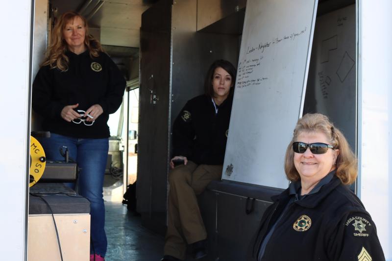 Photograph of three female SWAT Negotiators in the back of a vehicle with white board showing notes