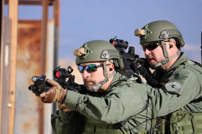 Photograph of SWAT Officers in tactical gear pointing rifles with scopes