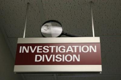 Photograph of Investigation Division sign in hallway with large magnifying glass on the top of sign