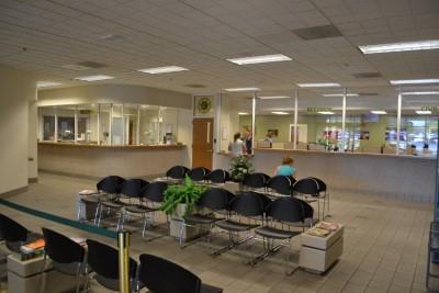 Photograph of lobby of Mesa County Sheriff's Office building showing the Records Lobby with waiting area with chairs and the office area through the window in the background