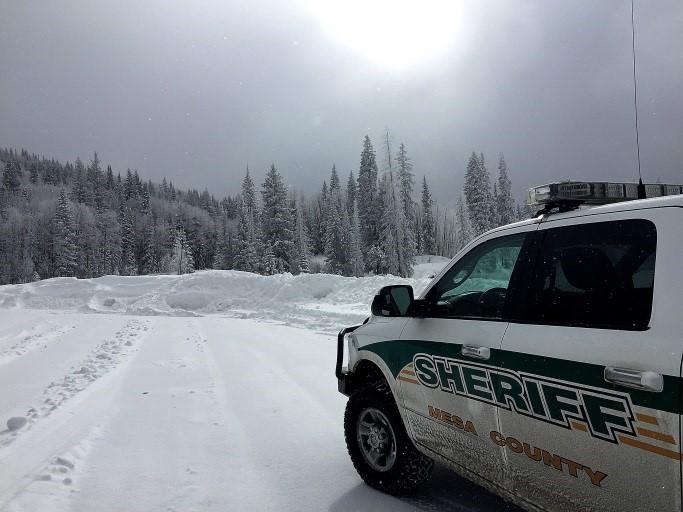 Photograph of Mesa County Sheriff Vehicle driving on a snow packed road in the mountains.