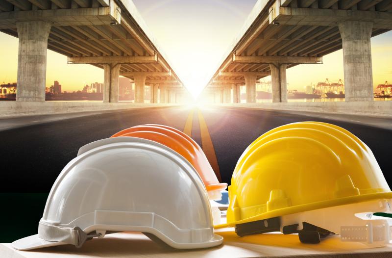 Concept photograph for Development Engineering.  Photograph of safety helmet on table, bridge construction and road in background