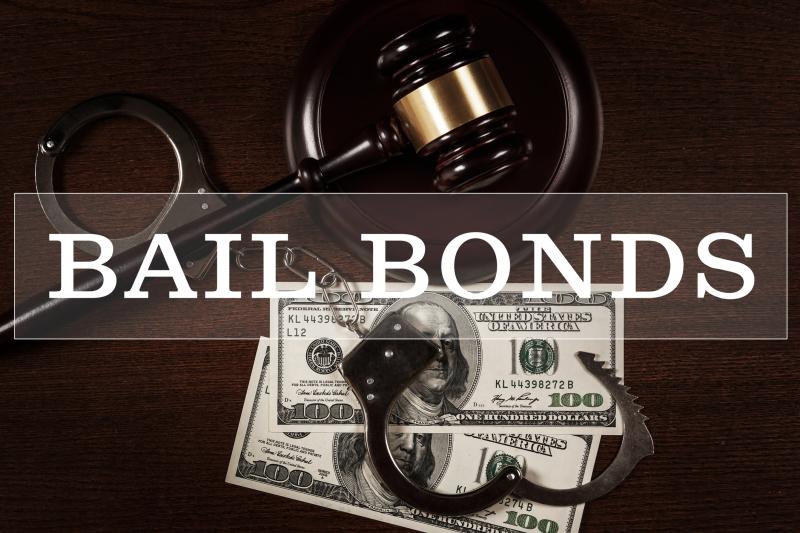 Photograph of Bail bonds services concept. Judge gavel, handcuffs and money on wooden background.