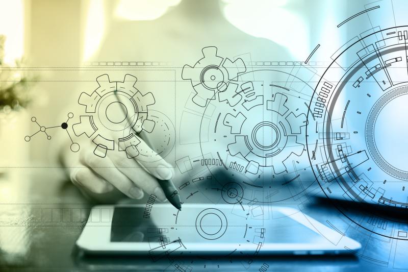 Concept photograph for development engineering.  Image with technology interface, gears, draft, table, man sitting at desk with pointer hovered over tablet.