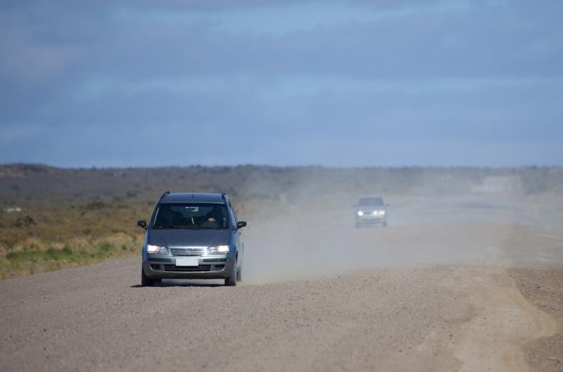 Photograph of Dusty Gravel Road. Cars driving along a dusty road