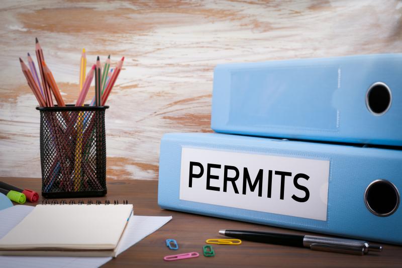 Concept photograph for Permits.   Office Binder on Wooden Desk. On the table colored pencils, pen, notebook paper.