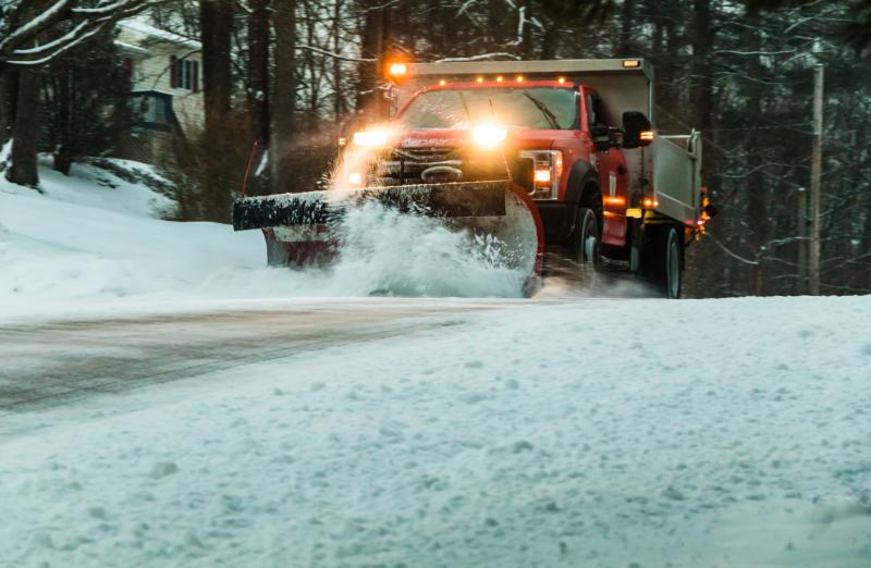 Photograph of Snow plow maintaining roads in a residential neighborhood during snow storm