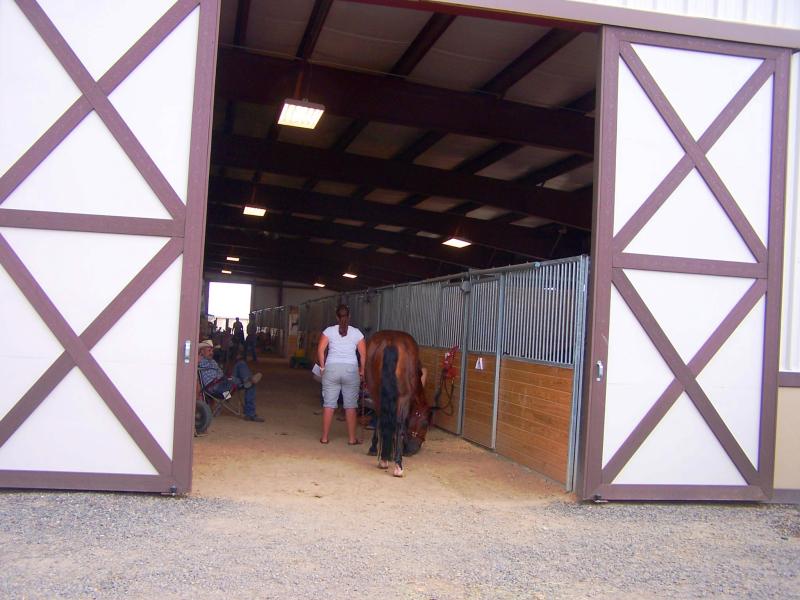 Photograph of interior of stables with people and horses