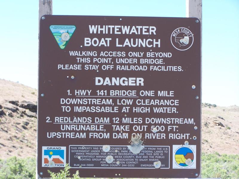 Boat launch sign that mentions walking access only beyond it, to stay off railroad facilities, and the danger items of low clearance and dam downstream