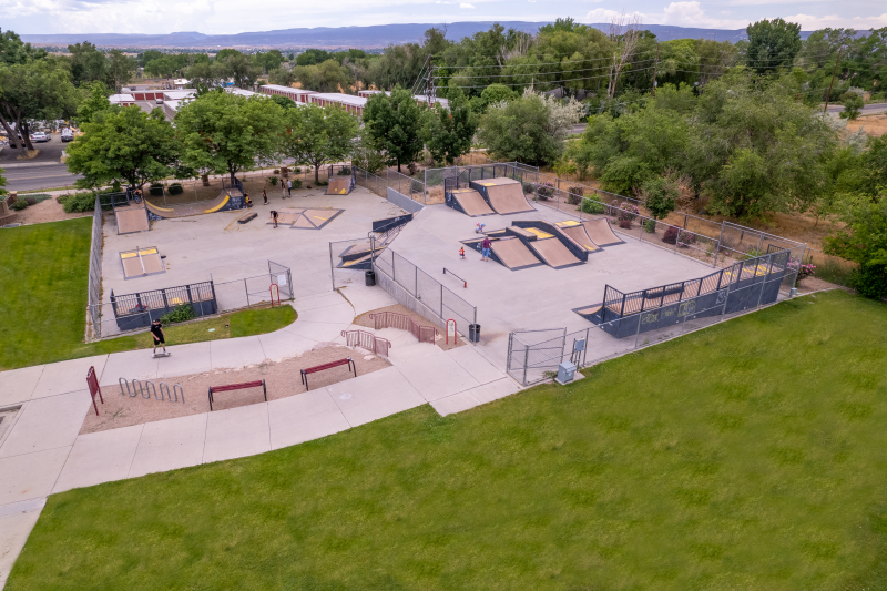Aerial view of the skateboard park with multiple jumps, ramps and other features enclosed in a chain link fence