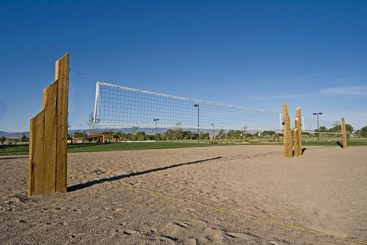 Two sand volleyball courts with nets strung surrounded by grass