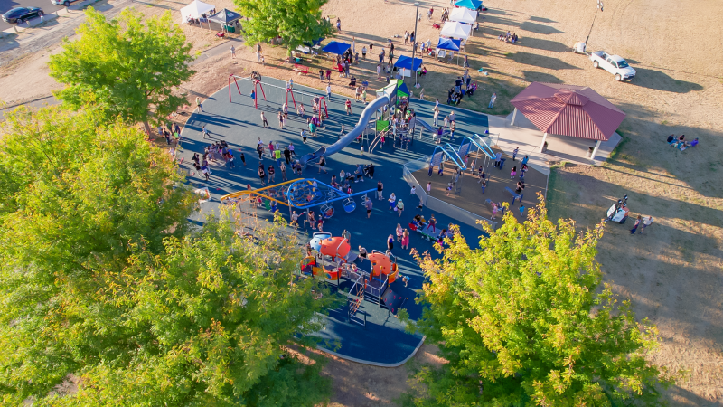 Aerial view of many kids and families gather at a park. 