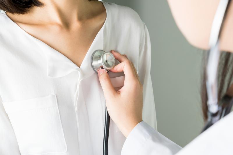 Doctor using stethoscope to listen to patient's heart.