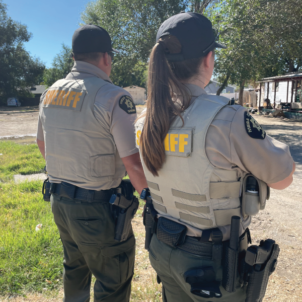 A female and male deputy stand with their backs to the camera in front of a house in Clifton.