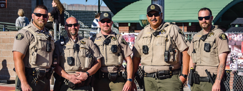 Five Mesa County Sheriff's Office School Resource Officers stand together outside during high school graduation in 2023.