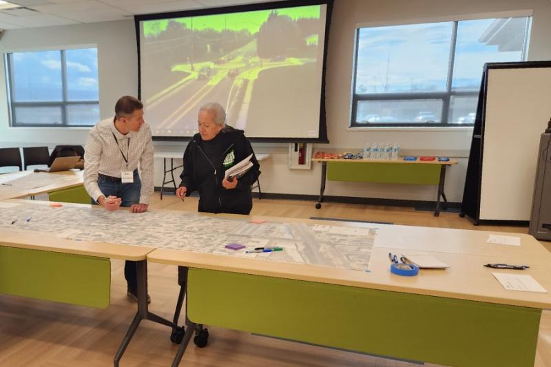 Two people talking and pointing to a map on a table. 
