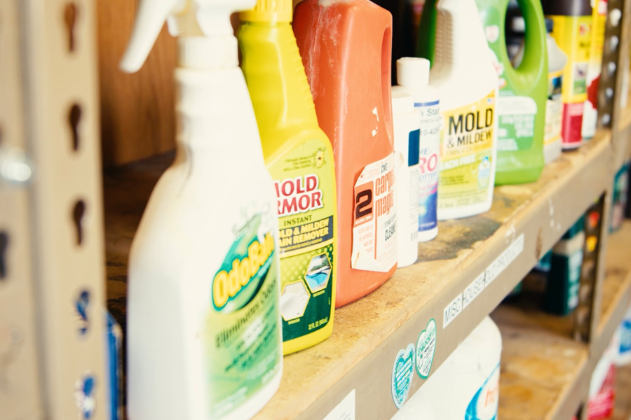 Variety of bright orange, yellow and white cleaning supplies sit on shelf. 