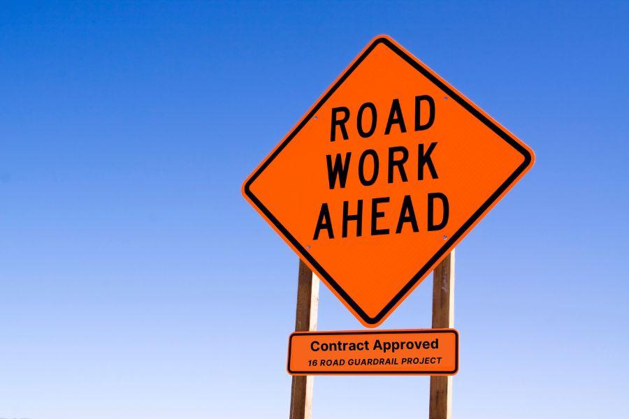 A road work ahead sign against the blue sky
