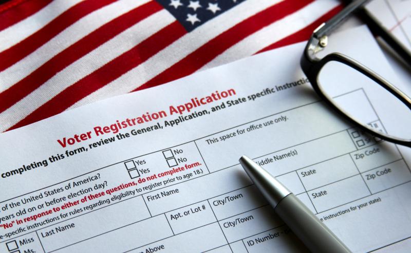 Photograph of Voter Registration Application with pen and glasses on US Flag